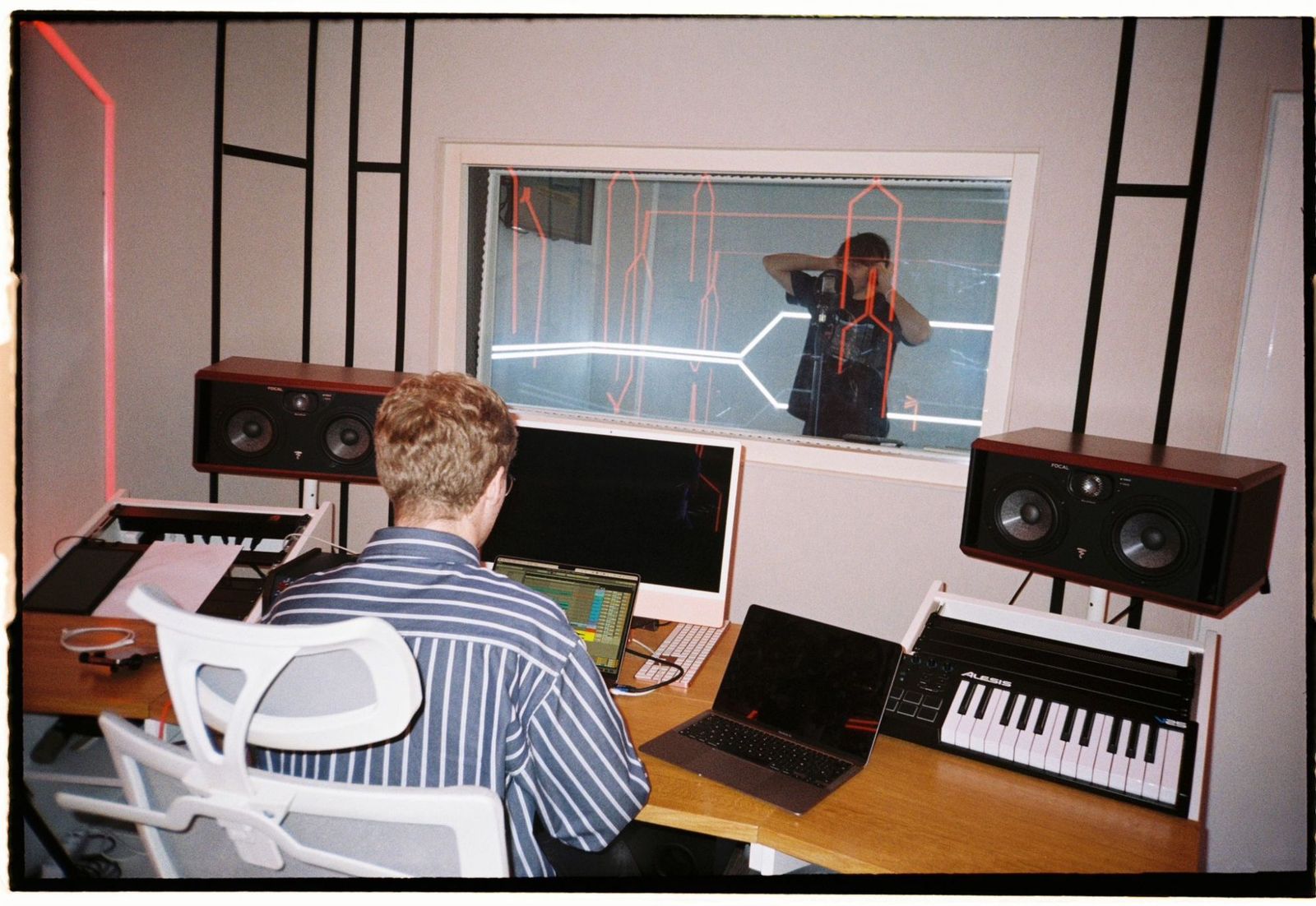 A control room seen from the desk, looking through the glass into the live room