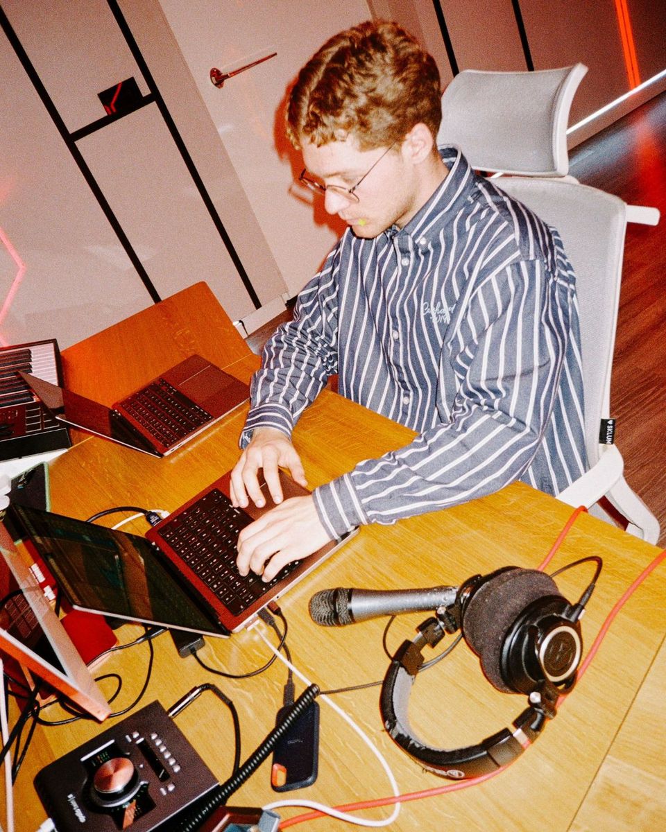 MrAnthony working at a laptop with a mic and headphones on the desk